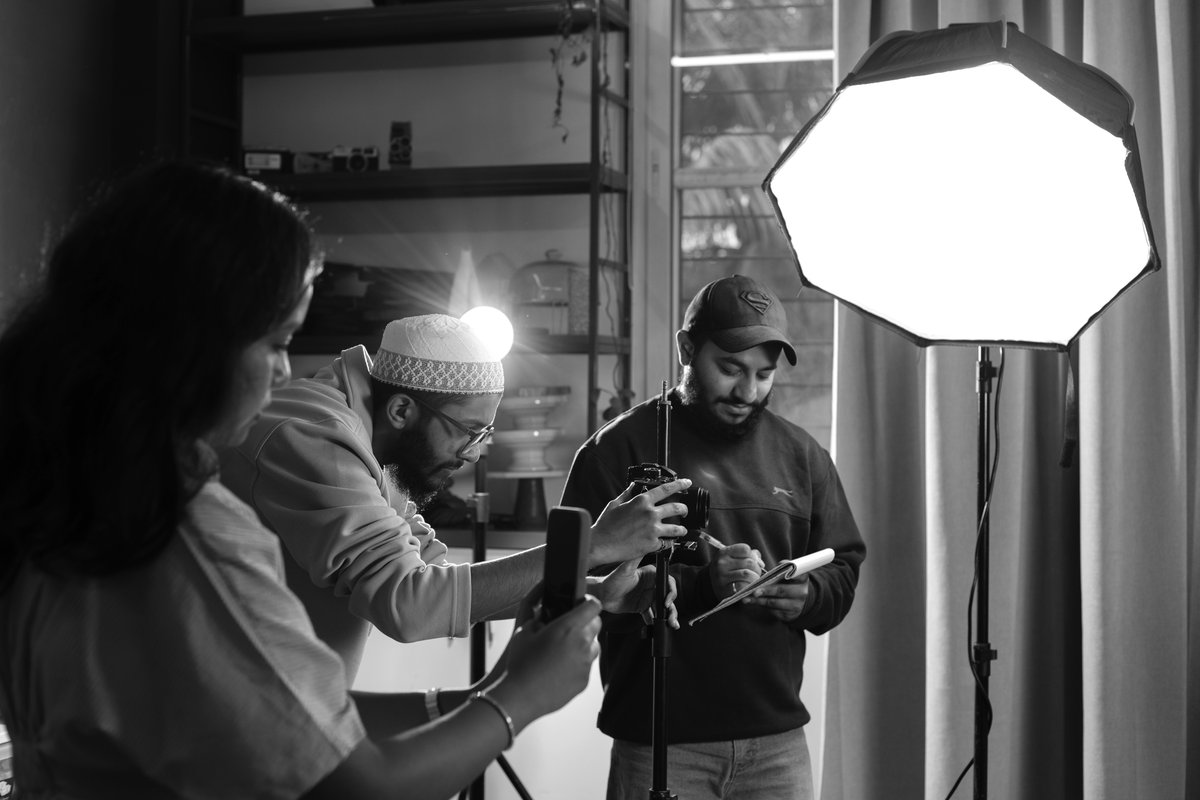 Crew checking a frame on camera under a softbox during a studio shoot