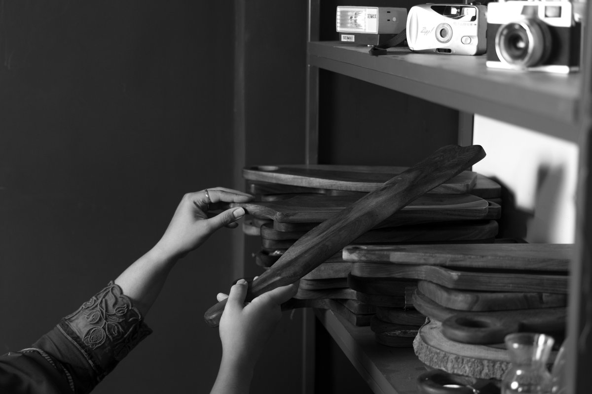 Hands arranging wooden serving boards on the studio prop shelf